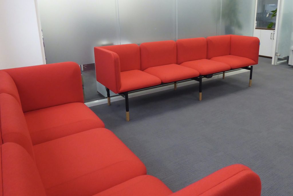 Office breakout space, with sofas upholstered in red fabric