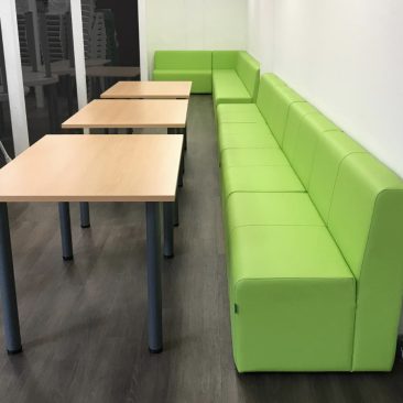 School common room with green modular seating in breakout area