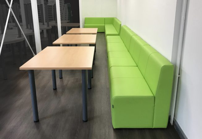 School common room with green modular seating in breakout area